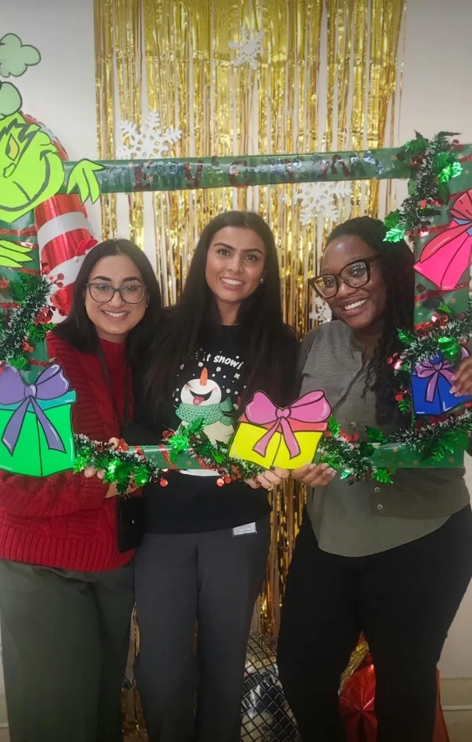 Jasraj and colleagues holding a Merry Christmas photo frame